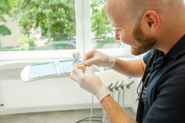 Ein Zahnarzt mit einem Gebissmodell in der Hand