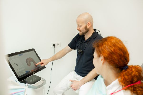 Zahnarzt zeigt Patientin digitalen Intraoralscan am Monitor